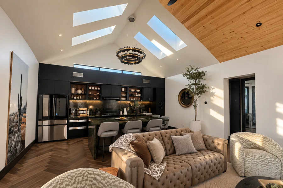 Casita & Guest House: Furnished open living room and dark kitchen cabinetry beneath a vaulted wood ceiling and skylights