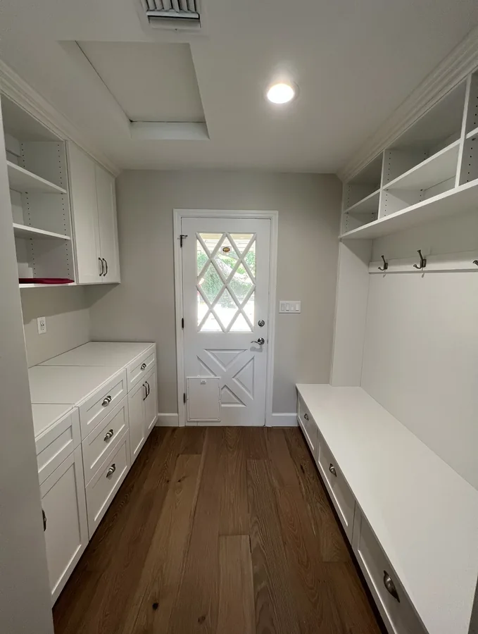 Central Corridor Remodel: Laundry room with white storage cabinetry, bench and hardwood flooring