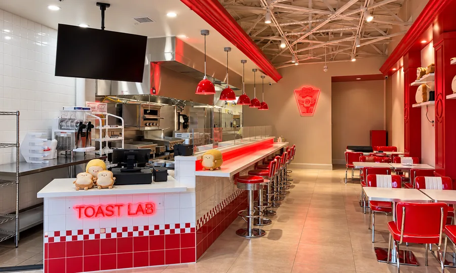 Let’s Toast Restaurant: Wide finished red/white restaurant interior facing check-out and serving counter